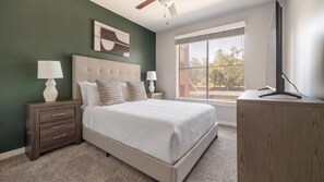 A bedroom with a bed, nightstands, a desk, a window, and a ceiling fan. - Landing | Stylish 2BD, Pool, Gym (Austin)