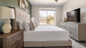 Een slaapkamer met een bed, een dressoir, een televisie en een raam met uitzicht.