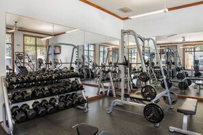 Ein Fitnessstudio mit Trainingsgeräten, Gewichtsbänken und einer Hantelbank.