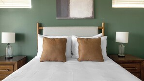 A neatly made bed with two pillows, a wooden headboard, and two bedside tables with lamps. - Landing | Chic 2BD, Gym, Pool (Austin)