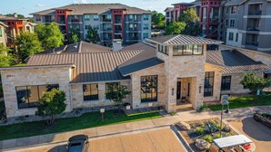 A residential building with a stone facade, multiple windows, and a parking area. - Landing | Beautiful 2BD, Pool, Gym (Austin)