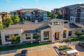 A residential building with a stone facade, multiple windows, and a parking area. - Landing | Beautiful 2BD, Pool, Gym (Austin)
