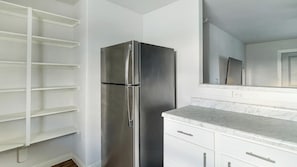 Una cocina con refrigerador de acero inoxidable, armarios blancos y encimera de mármol.