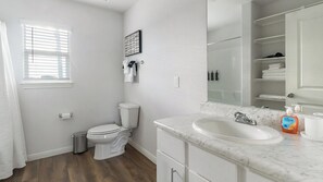 A bathroom with a toilet, sink, and mirror. - Landing | Stylish 1BD, Pool (Houston)