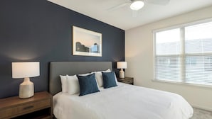 A bedroom with a bed, two bedside tables, a ceiling fan, a window with blinds, and a framed picture on the wall. - Landing | Amazing 1BD, Pool (Houston)