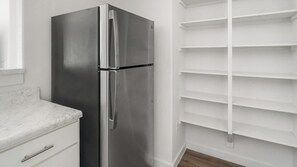 A stainless steel refrigerator in a kitchen with white cabinets and a marble countertop. - Landing | Stylish 1BD, Pool (Houston)