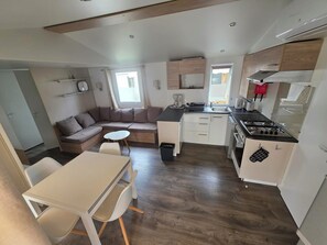 Eine kompakte Küche mit Essbereich, einem eingebauten Herd und einer Sitzecke mit Sofa und kleinem Tisch.