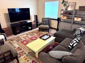Ein Wohnzimmer mit Flachbildfernseher, einer Couch, einem Couchtisch und einem gemusterten Teppich.
