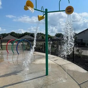 A water play area with multiple water jets and colorful rings. - Landing | Stunning 2BD, Pool (Houston)