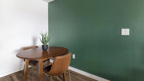 A dining area with a wooden table, two chairs, and a potted plant. - Landing | Chic 1BD, Pool (Houston)