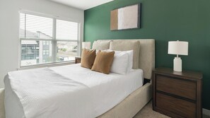 A bedroom with a bed, nightstands, a lamp, and a view through the window. - Landing | Beautiful 1BD, Pool (Houston)