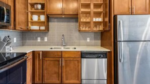 Eine Küche mit Holzschränken, einem Edelstahl-Kühlschrank und einem Geschirrspüler.