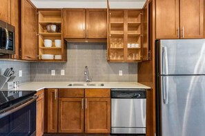 Eine Küche mit Holzschränken, einem Edelstahl-Kühlschrank und einem Geschirrspüler.