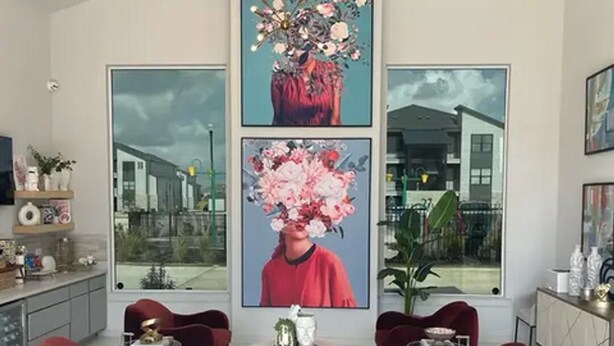 Ein modernes Wohnzimmer mit roten Sofas, einem runden Couchtisch und großen, gerahmten Blumenbildern an den Wänden.