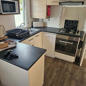 A compact kitchen with a microwave, toaster, sink, dishwasher, and a stove with oven. - The Mar Estang Oasis (Canet-en-Roussillon)