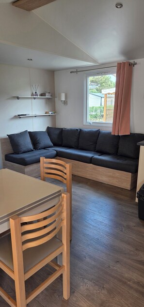 Ein modernes Wohnzimmer mit einem Ecksofa, einem Holzesstisch und Stühlen.