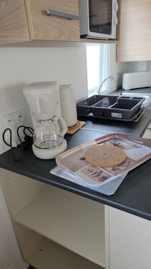 Eine Küche mit Mikrowelle, Toaster, Kaffeemaschine und einer Platte mit einem Keks.