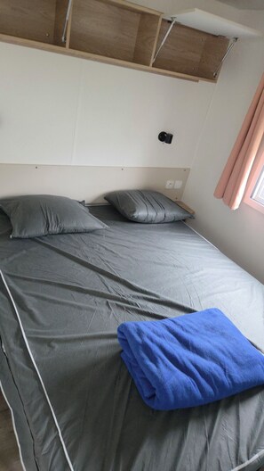 A single bed with grey bedding and pillows, a blue towel, and a wooden headboard. - The Mar Estang Oasis (Canet-en-Roussillon)