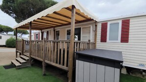 A covered outdoor deck with a wooden railing, a small step leading up to the deck, and a trash bin to the right. - The Mar Estang Oasis (Canet-en-Roussillon)