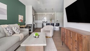 A modern living room with a sofa, coffee table, and a TV. - Landing | Incredible 1BD, Yoga Studio, Gym (Sarasota)