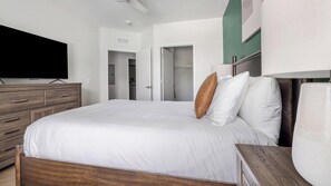 A bedroom with a bed, wooden dresser, and a television. - Landing | Incredible 1BD, Yoga Studio, Gym (Sarasota)