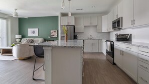 A modern kitchen with white cabinets, a granite countertop, and stainless steel appliances. - Landing | Spectacular 1BD, Gym, Yoga Studio (Sarasota)