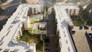 Een modern hotelcomplex bestaande uit meerdere gebouwen, een centrale binnenplaats met zwembad en een parkeerplaats.
