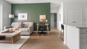 A modern living room with a sofa, coffee table, and artwork on the wall. - Landing | Spectacular 2BD, Yoga Studio, Gym (Sarasota)