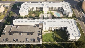 Un hotel a più piani con piscina sul tetto, parcheggio e aree verdi.