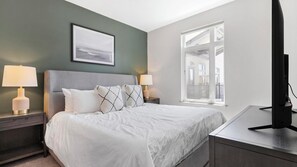 A hotel room with a bed, two bedside lamps, a framed picture on the wall, and a window with a view. - Landing | Incredible 1BD, Yoga Studio, Gym (Sarasota)