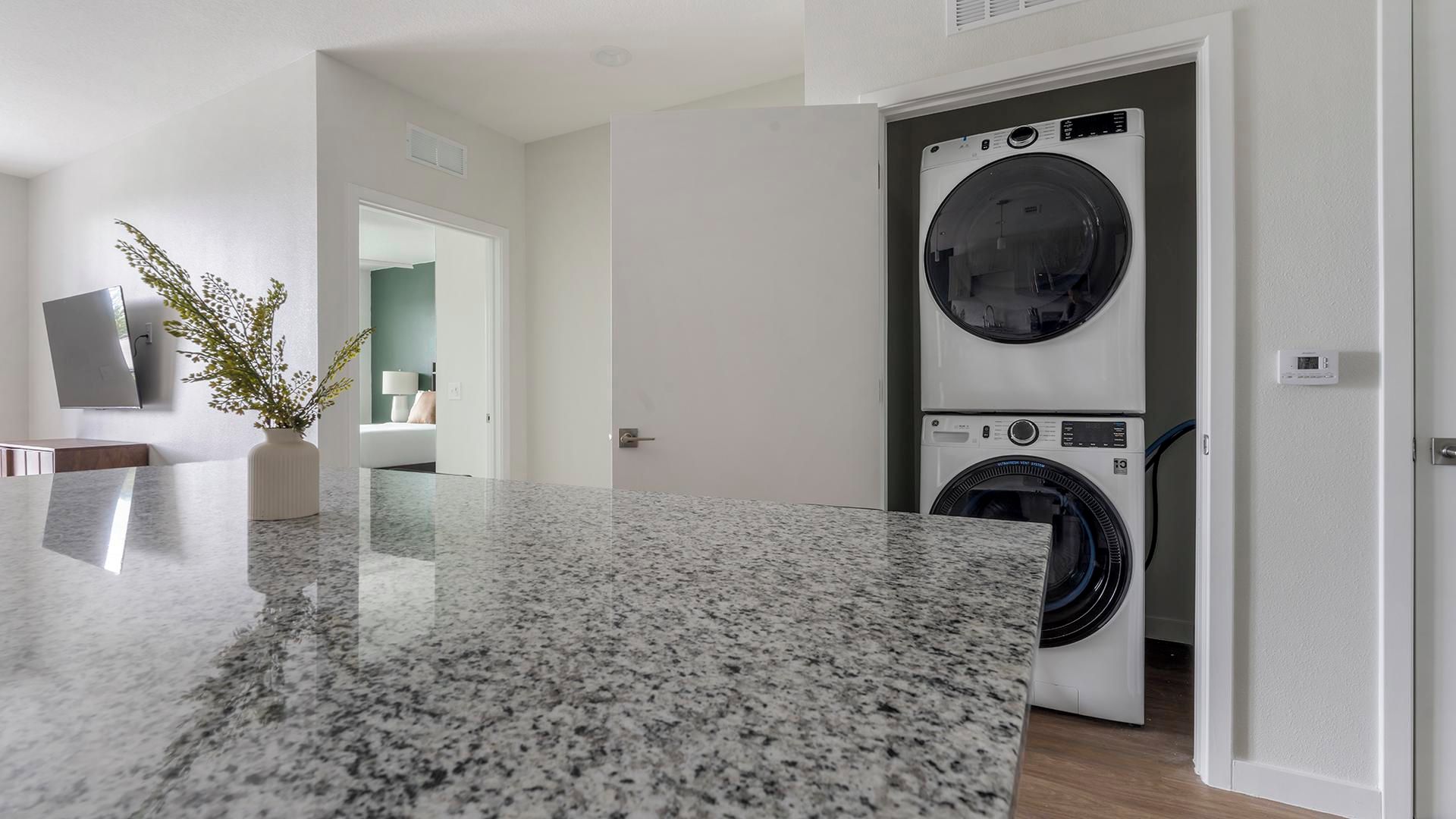 Eine moderne Küche mit Granit-Arbeitsplatten und einer integrierten Waschmaschine und einem Trockner.