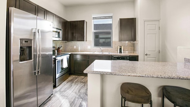 A modern kitchen with stainless steel appliances, granite countertops, and dark wood cabinets. - Landing | Spectacular 2BD, Gym, Yoga Studio (Sarasota)