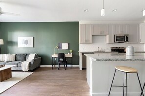 A modern kitchen with white cabinets, a granite countertop, and a stainless steel microwave. - Landing | Beautiful 1BD, Gym, Yoga Studio (Sarasota)