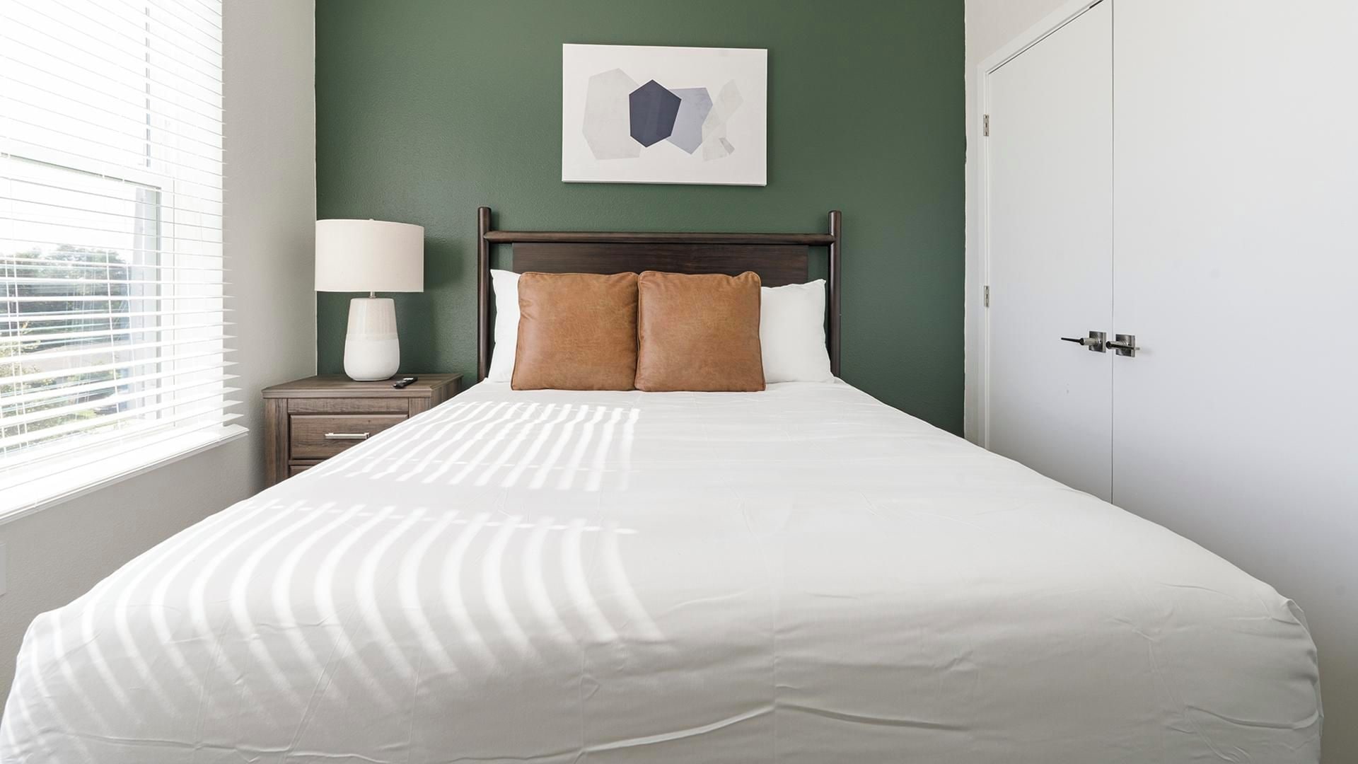 A neatly made bed with white linens, a wooden headboard, and two brown pillows.