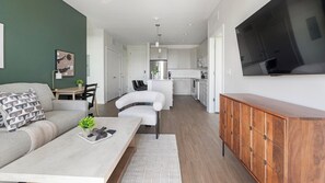 A modern apartment with a living room, dining area, kitchen, and a TV mounted on the wall. - Landing | Beautiful 2BD, Gym, Yoga Studio (Sarasota)