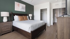Ein Schlafzimmer mit einem Bett, Nachttischen, einem Schminktisch und einem begehbaren Kleiderschrank.