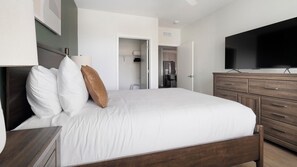 Een hotelkamer met een bed, een televisie, een dressoir en een badkamer die door een open deur zichtbaar is.