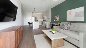 Een moderne woonkamer met een flatscreen televisie, een houten salontafel en een grijze bank.
