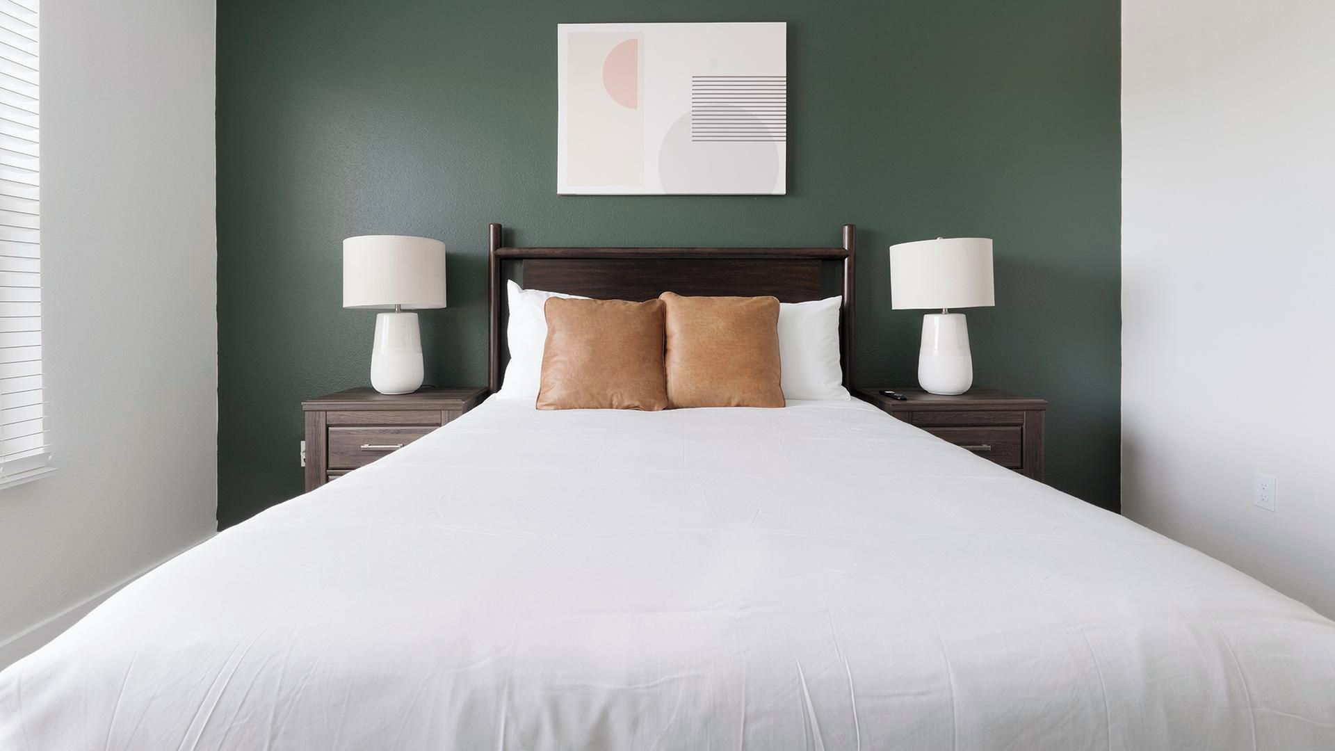 Une chambre d’hôtel avec un grand lit, deux tables de chevet avec des lampes et une œuvre d’art accrochée au mur.