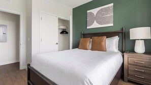 A neatly made bed with white linens, a wooden headboard, and two pillows, one brown and one white. - Landing | Amazing 2BD, Gym, Yoga Studio (Sarasota)