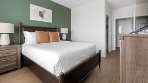 A neatly arranged bedroom with a bed, bedside tables, and a dresser. - Landing | Chic 1BD, Gym, Yoga Studio (Sarasota)