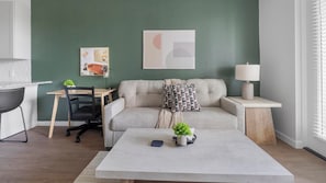 A modern living room with a sofa, coffee table, and a desk with a chair. - Landing | Chic 1BD, Gym, Yoga Studio (Sarasota)