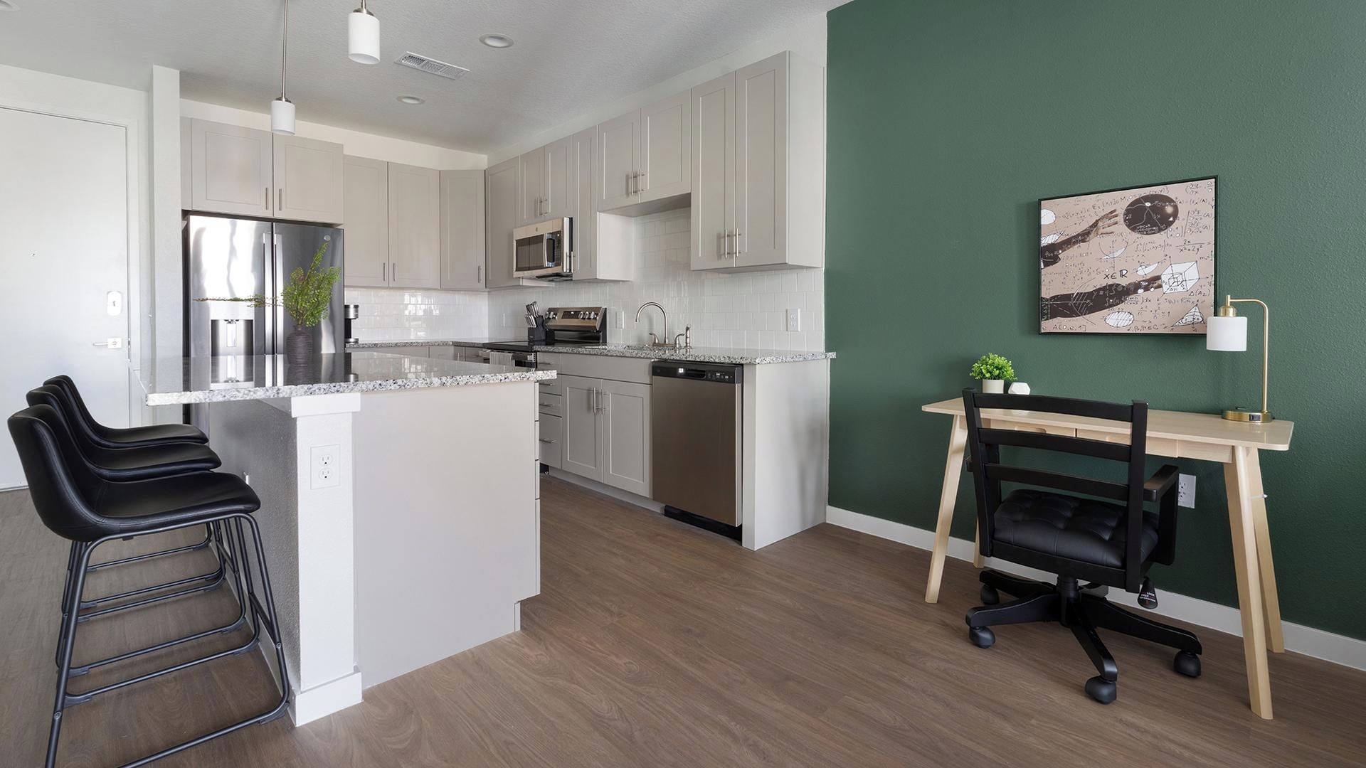 A modern kitchen with white cabinets, stainless steel appliances, and a wooden island with bar stools.