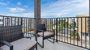 A balcony with wicker furniture and a view of a residential area. - Landing | Spectacular 1BD, Gym, Yoga Studio (Sarasota)