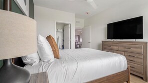 Ein Schlafzimmer mit einem Bett, einem Schminktisch, einem Fernseher und einer Tür zu einem Badezimmer.