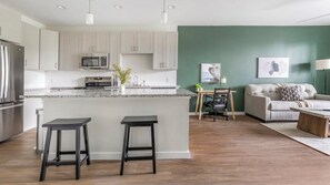 Eine moderne Küche mit einer zentralen Kochinsel, Barhocker und einem Essbereich mit Tisch und Stühlen.