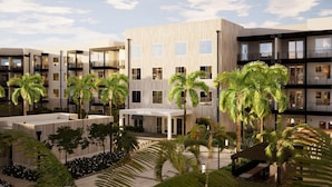 A modern multi-story hotel with a central courtyard featuring palm trees and a covered seating area. - Landing | Stunning 1BD, Gym, Yoga Studio (Sarasota)