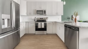 Eine moderne Küche mit Edelstahlgeräten, weißen Schränken und einer Arbeitsplatte aus Granit.