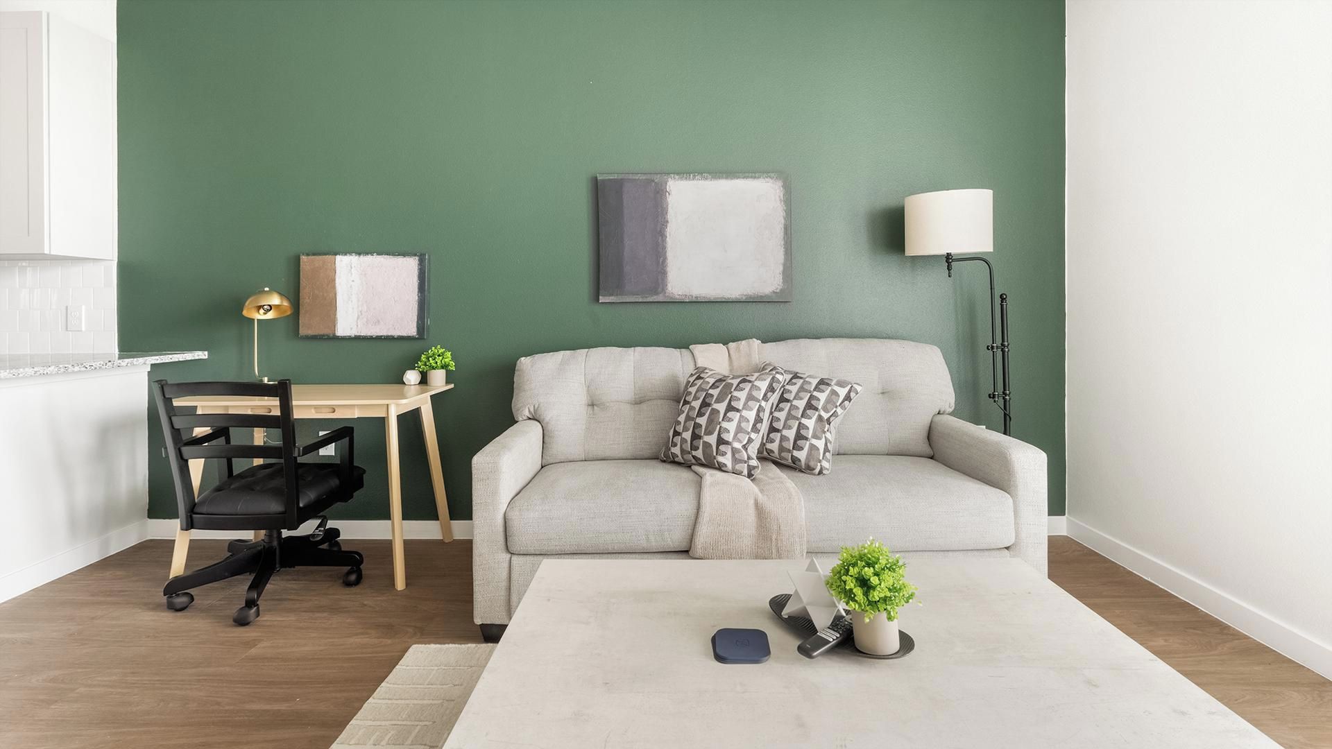 A modern living room with a sofa, a desk, and a lamp.