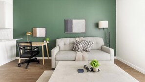 A modern living room with a sofa, a desk, and a lamp. - Landing | Stylish 1BD, Gym, Yoga Studio (Sarasota)